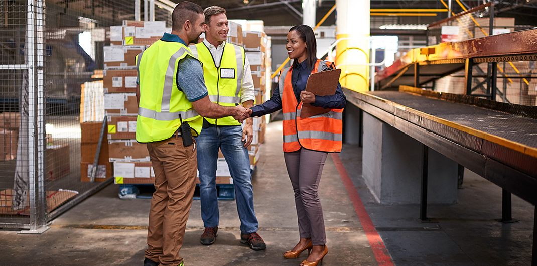 logistics workers shake hands in a distribution warehouse