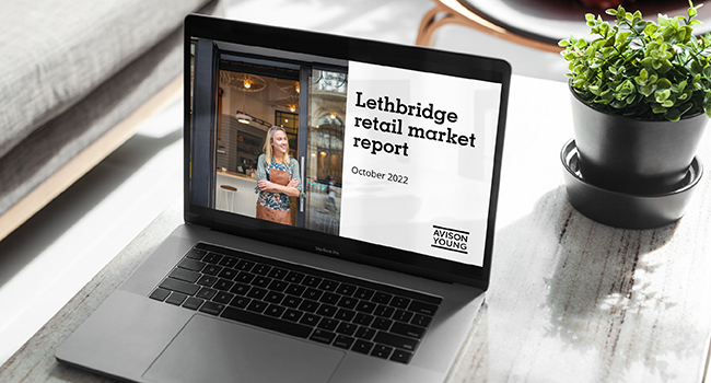 photo of a laptop on a coffee table displaying the Avison Young Lethbridge retail market report October 2022