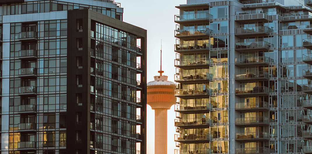 view of CN tower between two office high rise buildings in Toronto